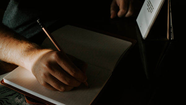 Man writing in journal using a guided journaling prompt