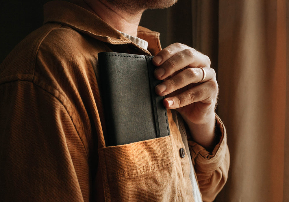 A man with a black pocket journal in his front coat pocket.